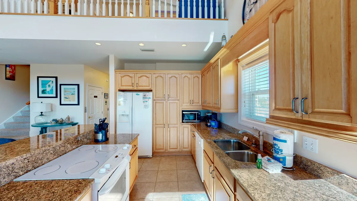 This image focuses on a chef-inspired kitchen with granite countertops, wooden cabinetry, and quality appliances. The area is designed for both cooking and socializing, with a feel that invites guests to gather at the breakfast bar or participate in meal preparation.