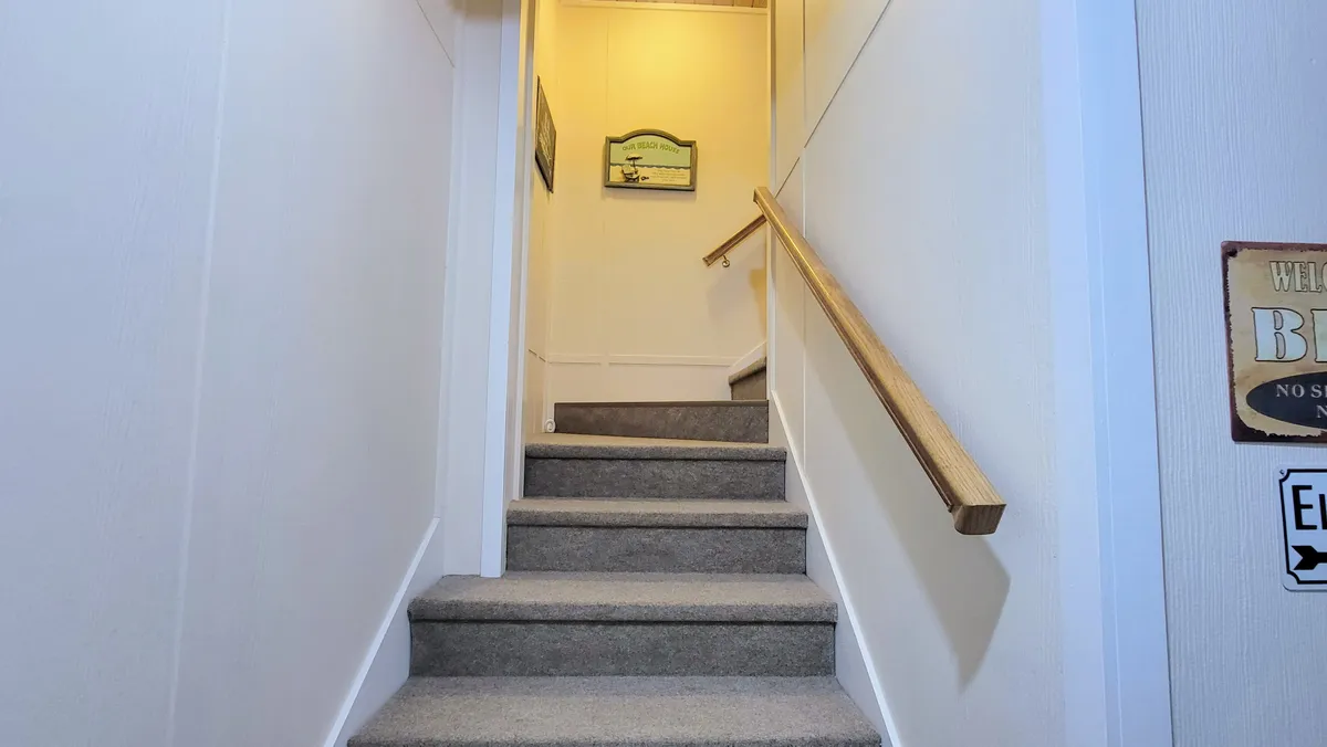 A warmly lit staircase with a secure wooden handrail and decorative wall elements, inviting residents to explore the upper levels. The staircase’s design suggests sturdy, supportive features and easy navigation between floors.